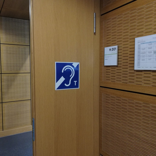 Hörschleife Hörsaaltür mit einem Schild des Symbolbilds für einen Hörschleife
