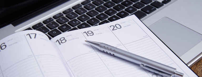 Kalender, Stift und Tastatur Aufgeschlagener Taschenkalender mit einem Stift auf einer Tastatur