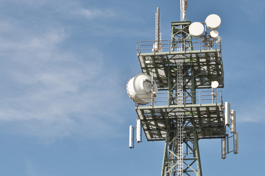Mast mit verschiedenen Antennen vor blauem Himmel