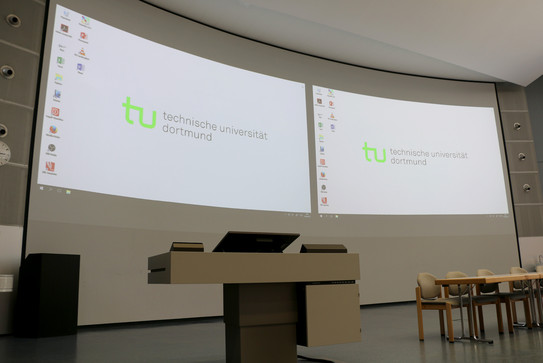 Lecture hall console in front of the curved projection screen in the Audimax