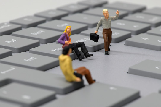 Miniaturmenschen Zwei sitzende und ein laufender Miniaturmensch auf einer Tastatur