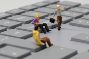 miniature humans Two sitting and one running miniature human on a keyboard